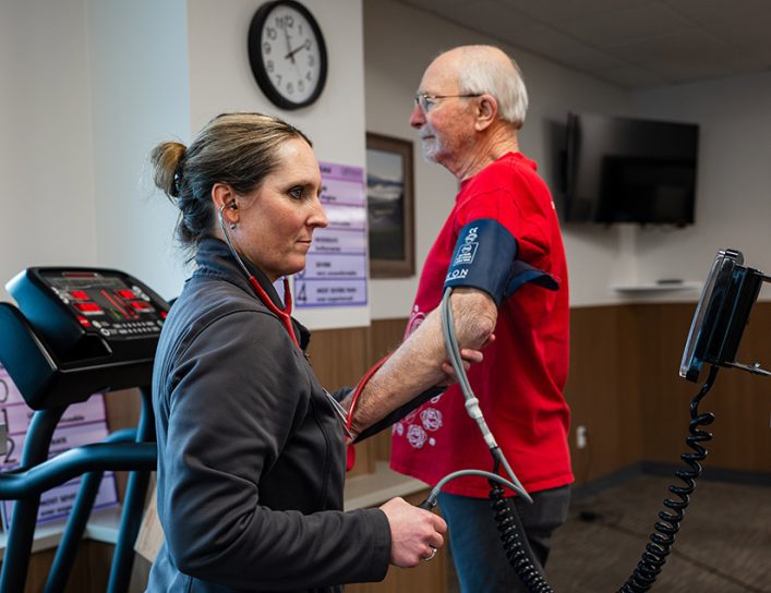 Medical worker monitoring heart health patient on treadmill.